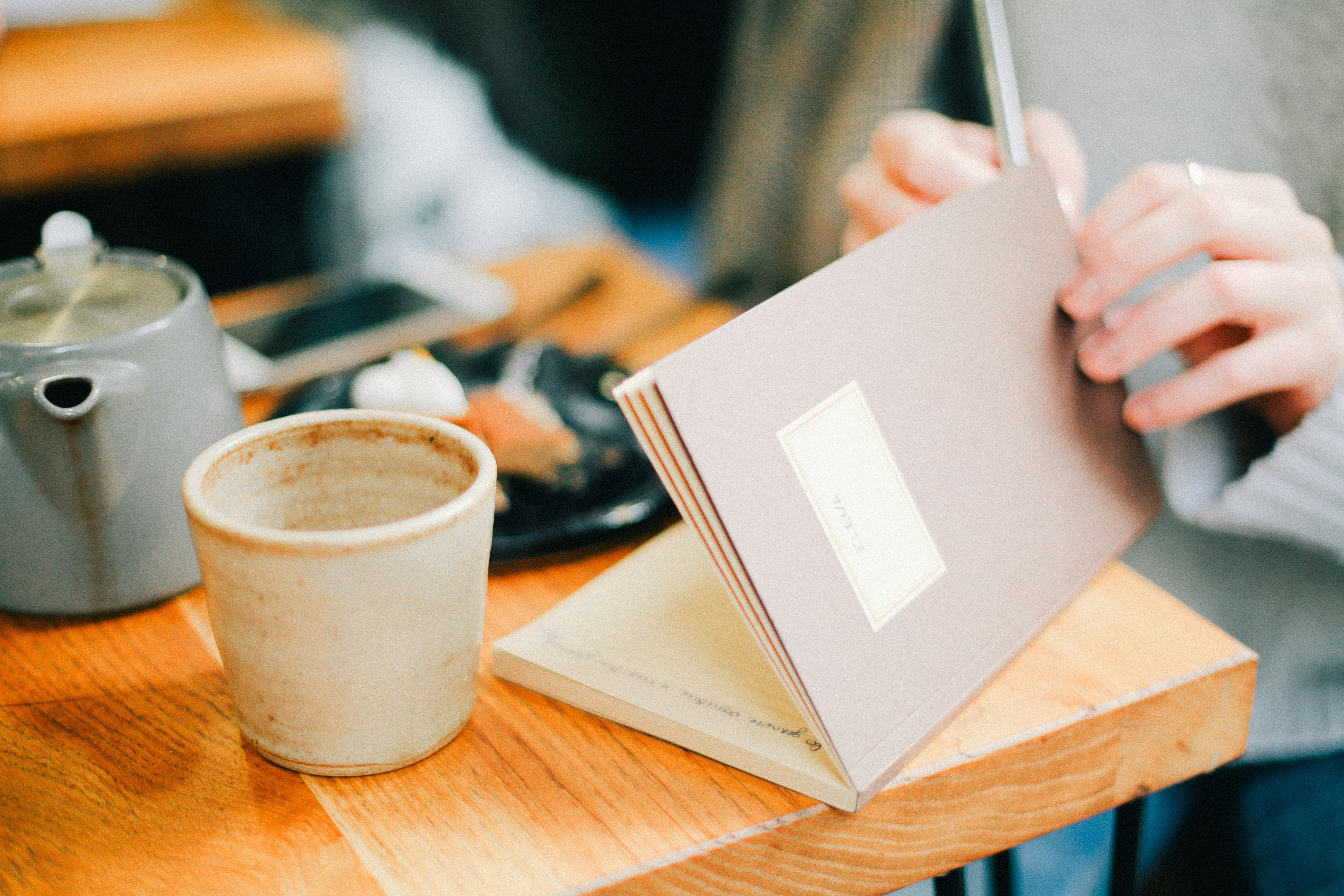 woman journaling with a hot drink in a cafe