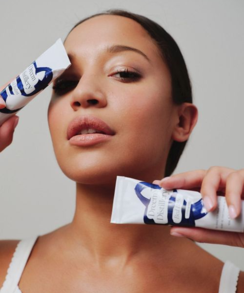 Woman holdng two tubes of Dreem Distillery CBD balm