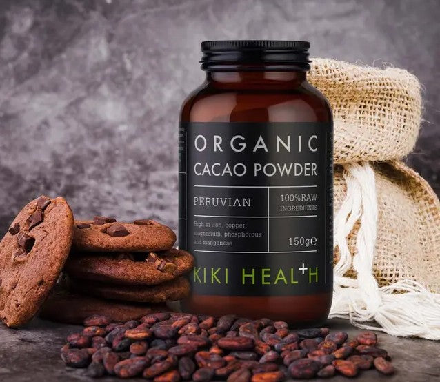 KIKI Health Organic Cacao Powder bottle with cookies and cacao beans on a dark background