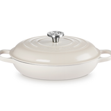 A cream-colored enameled cast iron casserole dish with a matching lid and side handles, featuring a silver metal knob on a clean white background.