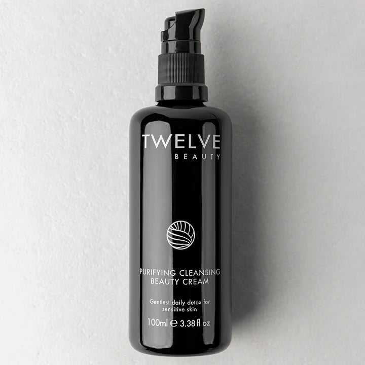 A 100ml black pump bottle of Twelve Beauty Purifying Cleansing Beauty Cream, set against a textured light gray background.